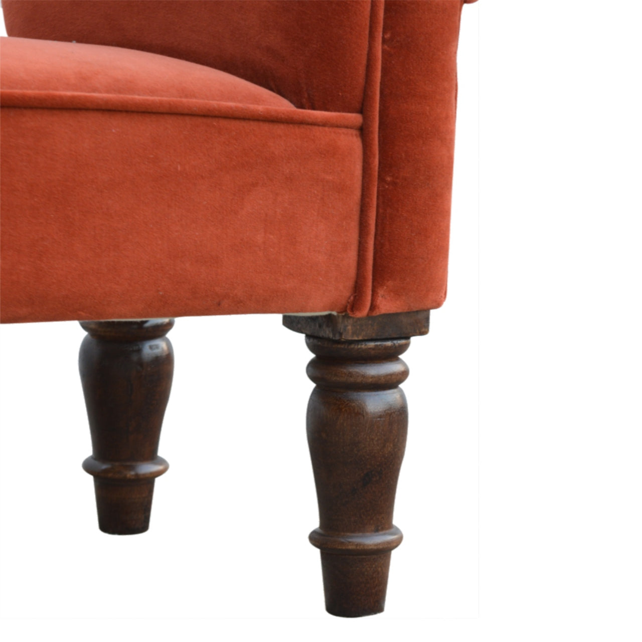 Close-up of a rust-colored velvet armchair with wooden legs on a white background
